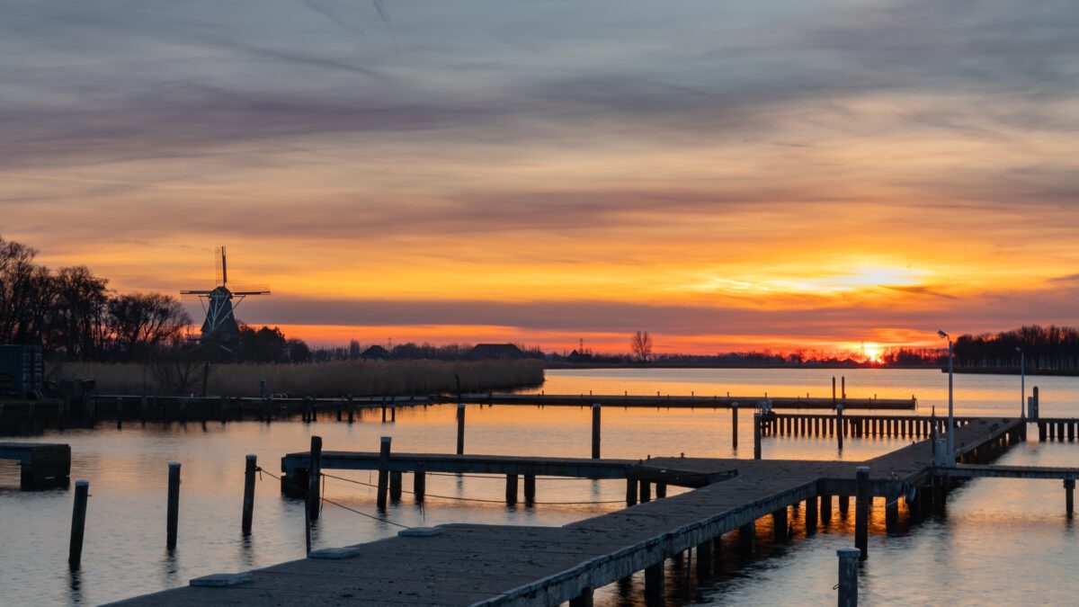 Saharazand zorgt voor een kleurexplosie tijdens zonsondergang boven de haven en molen van Anna Paulowna