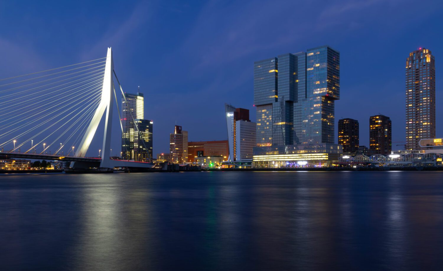 Sky line Rotterdam by night met zicht op de Erasmusbrug en De Rotterdam vanaf de oever van de Maas