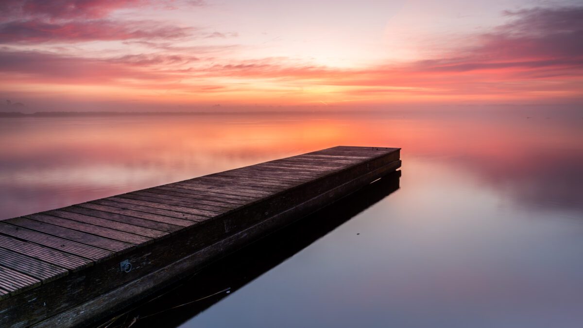 Prachtige kleuren in de lucht tijdens een mistige zonsopkomst boven de steiger van het Meer van Dirkshorn