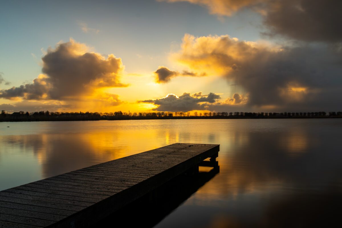 Steiger in het Meer van Dirkshorn met wegdrijvende regenwolken en een opkomende zon