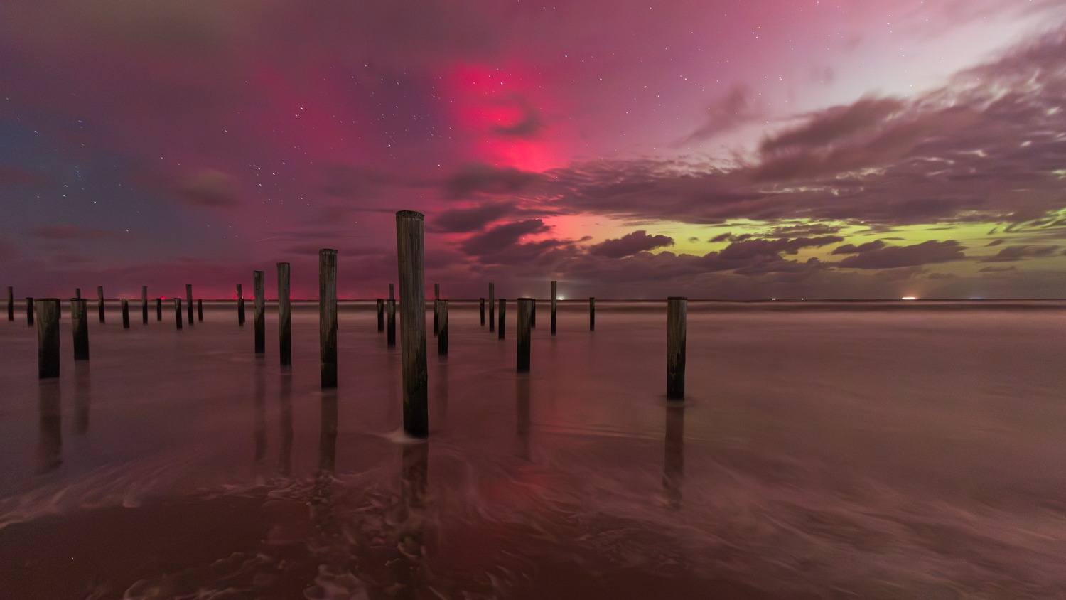 Het spectaculaire Noorderlicht is goed te zien boven het monumentale palendorp op het strand bij Petten.