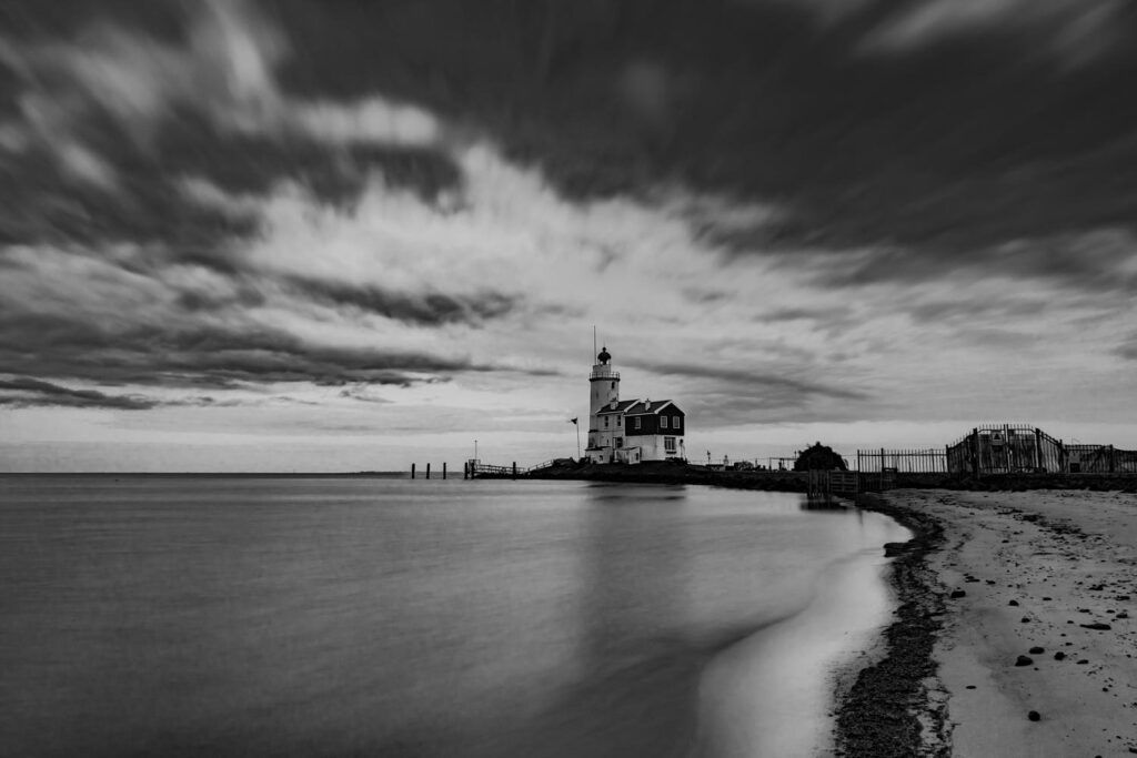 Ruig Marken - Vuurtoren Het Paard van Marken aan het Markermeer onder een dreigende lucht van regenwolken, uitgevoerd in zwartwit.
